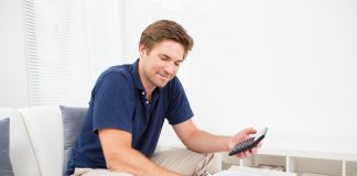 Smiling adult man calculating home finances at table