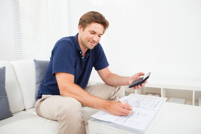 Smiling adult man calculating home finances at table