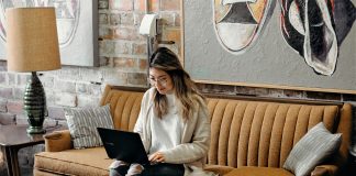 Woman working at laptop and sitting on couch