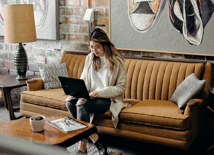 Woman working at laptop and sitting on couch