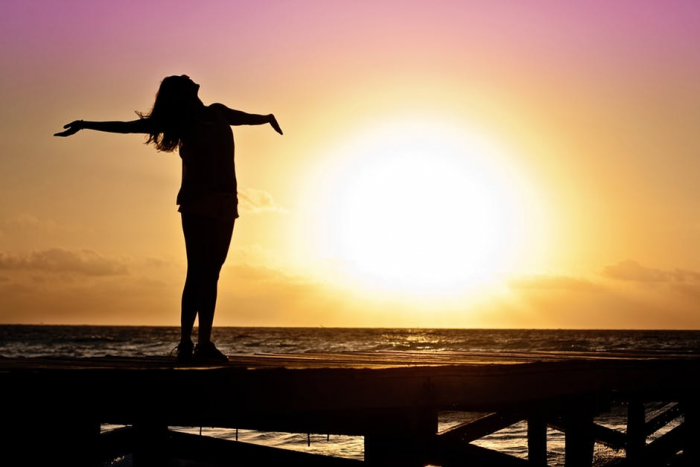 Happy woman standing against sunset