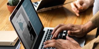 Businessperson typing on laptop while colleague watches