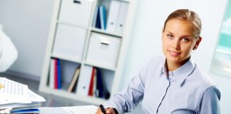 Portrait of a young happy businesswoman looking at camera while working in office