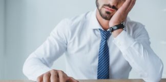 Tired financier counting money with calculator in office