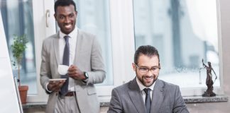 Smiling business partners looking at laptop in office