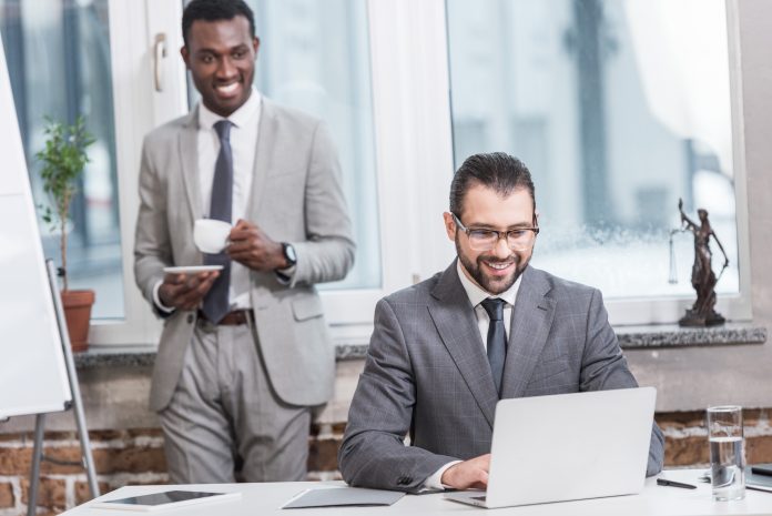 Smiling business partners looking at laptop in office