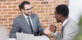 Businessmen smiling and talking at table with laptop