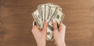 Top view of woman holding dollars banknotes on wooden background