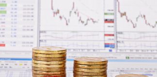 Downtrend coin stacks, red pencil, financial chart as background