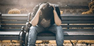 Man sitting on bench with head in his hands