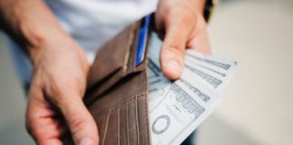 Man holding brown wallet with money in it