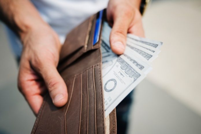 Man holding brown wallet with money in it