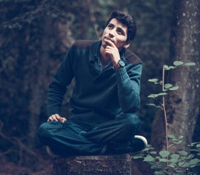 Man sitting on tree trunk and thinking