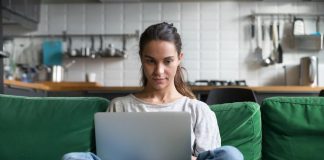 Woman working on laptop and sitting on couch