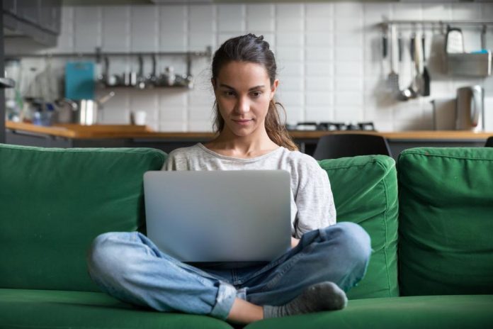 Woman working on laptop and sitting on couch