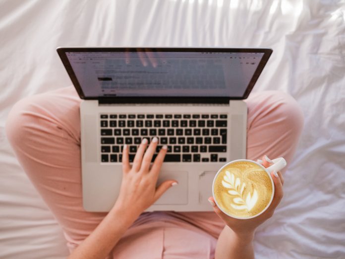 Woman working on her laptop and holding a coffee