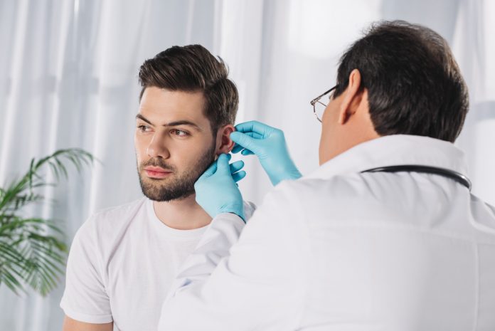 Doctor examining male patient's ear