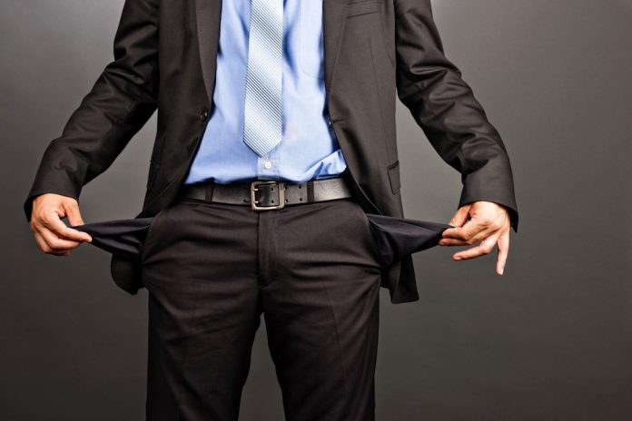 Businessman showing his empty pockets on gray background