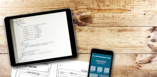 Website wireframe sketch and programming code on digital tablet