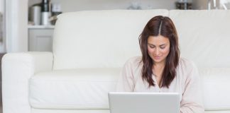 Woman sitting on the carpet typing on her laptop