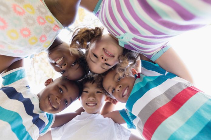 Smiling friends huddling against sky