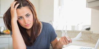 Woman looking worried over finances in kitchen