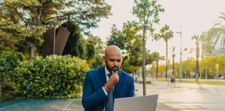 Businessman holding laptop notebook wearing blue suit near office