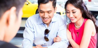 Couple signing contract for car at dealership