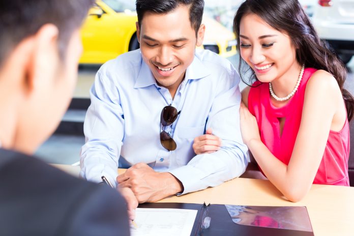 Couple signing contract for car at dealership