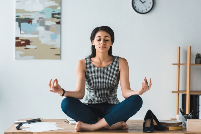 Businesswoman practicing yoga in office