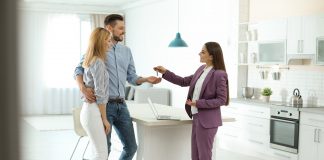 Real estate agent giving house key to couple indoors