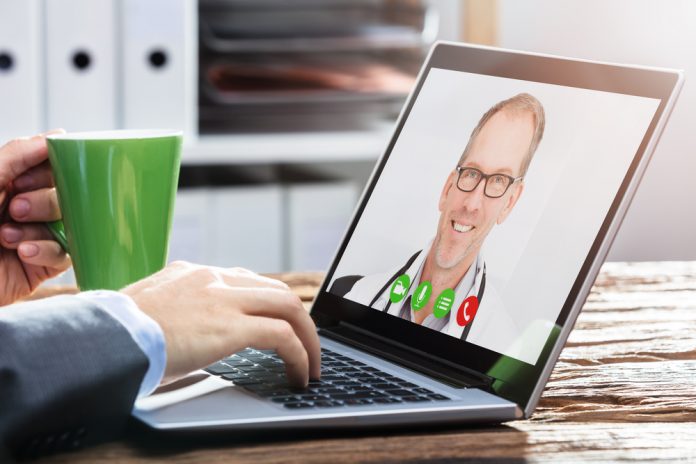 Person Video Conferencing with Doctor on Laptop