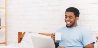 Businessman working on laptop with coffee in bed