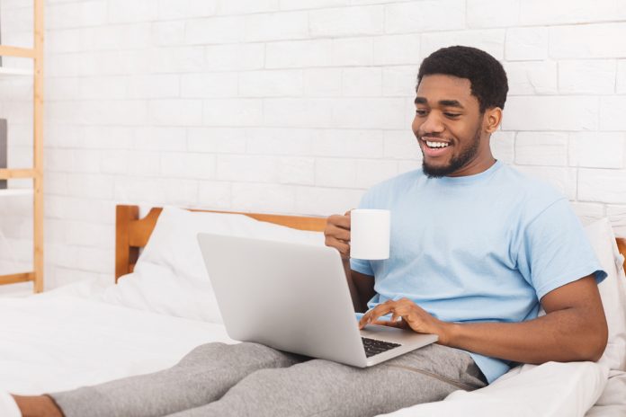 Businessman working on laptop with coffee in bed