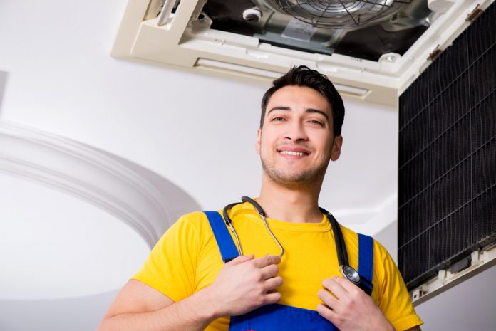 Repairman Repairing Ceiling Air Conditioning Unit