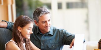 Father And Daughter Looking At Laptop Together