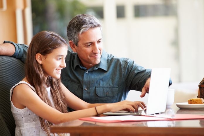 Father And Daughter Looking At Laptop Together