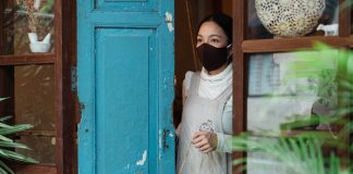 Woman wearing face mask opening shop