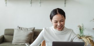 Woman Smiling While Working on Laptop