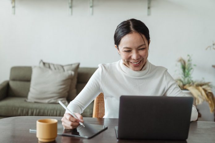 Woman Smiling While Working on Laptop