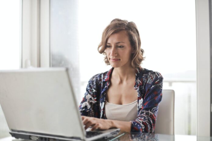 A Business Woman Working on Her Laptop and Considering the Benefits of Relocating a Home Business from Minnesota