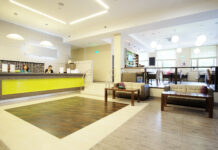 A business reception area with a large desk, a few sofas with tables, and bright, comforting lighting.