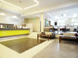 A business reception area with a large desk, a few sofas with tables, and bright, comforting lighting.