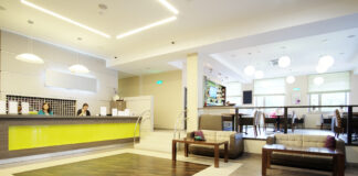 A business reception area with a large desk, a few sofas with tables, and bright, comforting lighting.