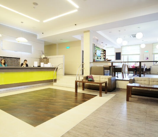 A business reception area with a large desk, a few sofas with tables, and bright, comforting lighting.