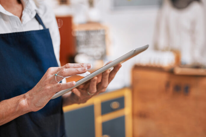 Hands, tablet and small business owner woman with e commerce, stock supply chain management and marketing for cafe. restaurant, barista and worker typing on digital technology or software network app Custom Retail Software Ecommerce