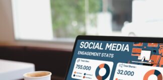 Someone typing on a laptop with a bunch of social media engagement stats on it. They have a cup of coffee next to them.