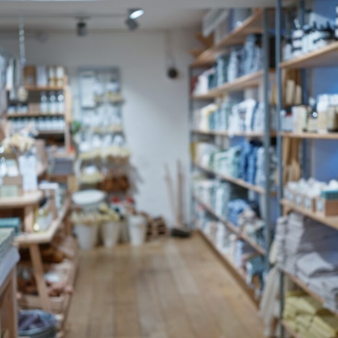 A well-organized retail store interior with wooden shelves displaying neatly arranged home goods, bath products, and decor items along a central aisle. A well-organized retail store interior with wooden shelves displaying neatly arranged home goods, bath products, and decor items along a central aisle.