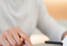 Hidden Liability Risks in Commercial Property Management A person is sitting at a desk and is typing on a computer with one hand and typing on a calculator with the other.