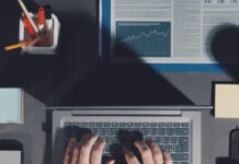 The Link Between Organization and Business Success An aerial view of someone sitting at their desk with their hands on the laptop in the center and office supplies around them.